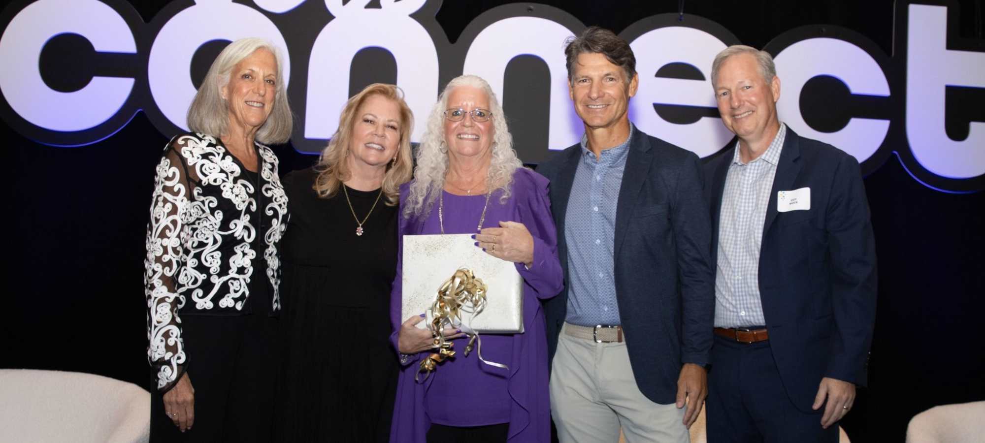 A Drucker + Falk team smiling with a gift