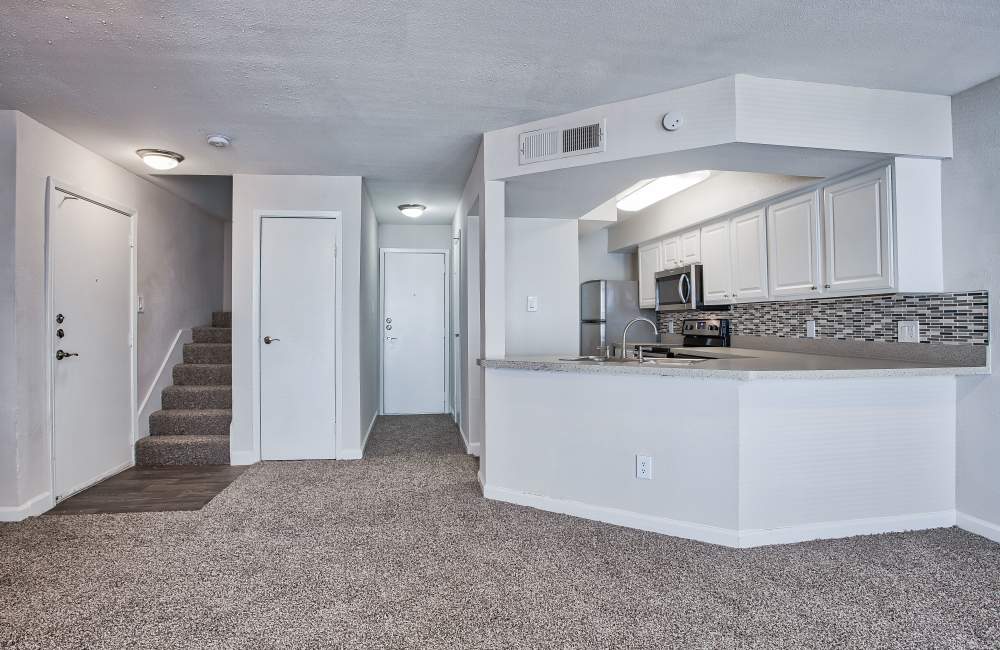 Modern apartment with view of kitchen and stairs to the next level at Branch Creek Apartments in Carrollton, Texas