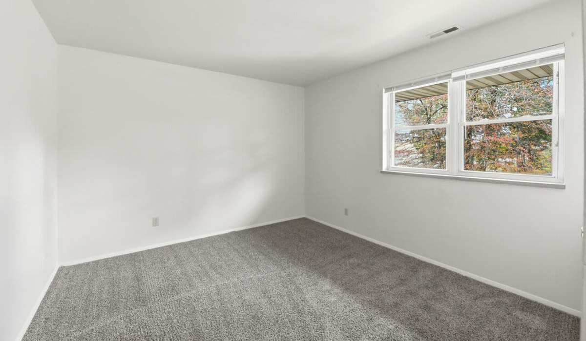 Bright and inviting bedroom with cozy carpeting and large windows showcasing a lovely view at The Reserve at Pin Oak Manor Apartments in Mishawaka, Indiana.