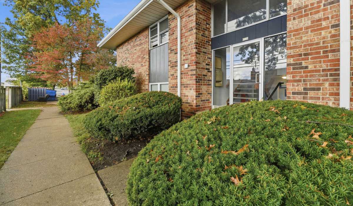 Charming entrance with lush landscaping at The Reserve at Pin Oak Manor Apartments in Mishawaka, Indiana.