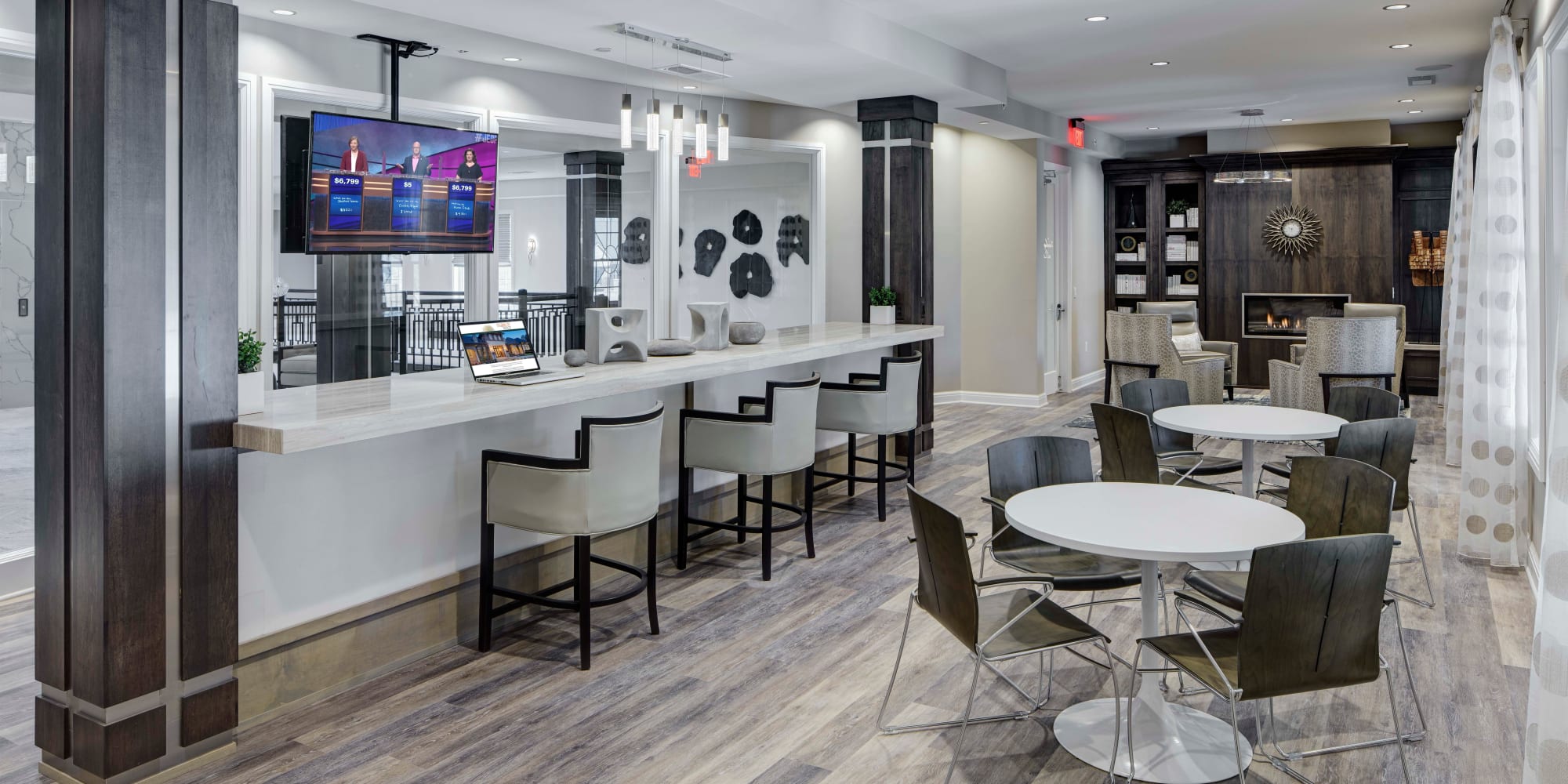 Cafe with several tables, a serving bar, and a tv mounted to the ceiling at Blossom Ridge in Oakland Charter Township, Michigan