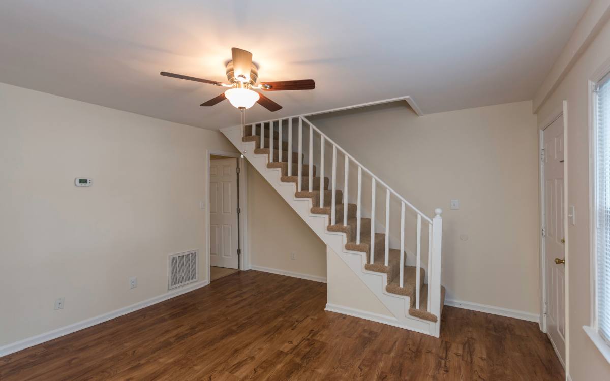 Living area with ceiling fan and the staircase to the upper level at Fox Chase Apartments in Fredericksburg, Virginia