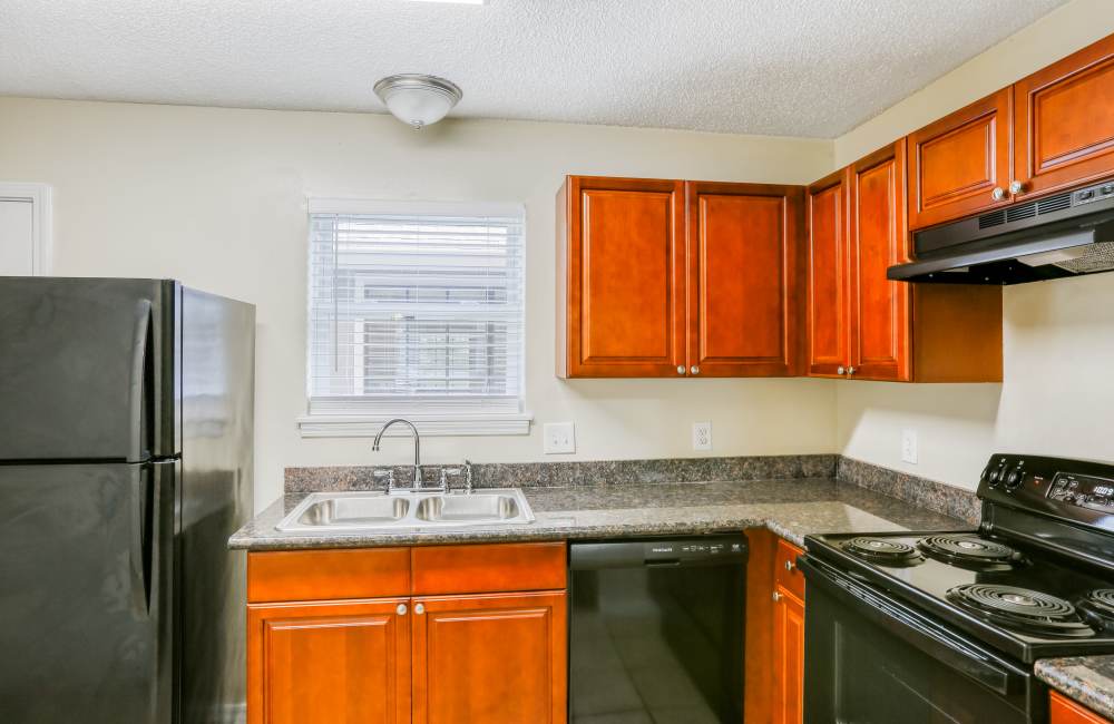 Well-equipped kitchen with granite counters and wooden cabinets at Creekwood Townhomes in Hammond, Louisiana