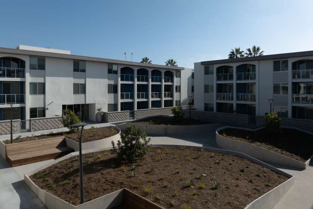 Luxury white buildings with balconies and landscaped area at Dolphin Marina Apartments in Marina Del Rey, California