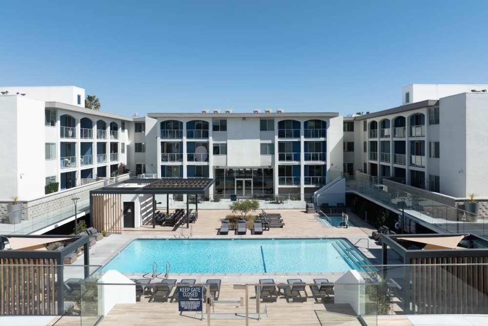 Luxury swimming pool with lounge chairs and cabana at Dolphin Marina Apartments in Marina Del Rey, California