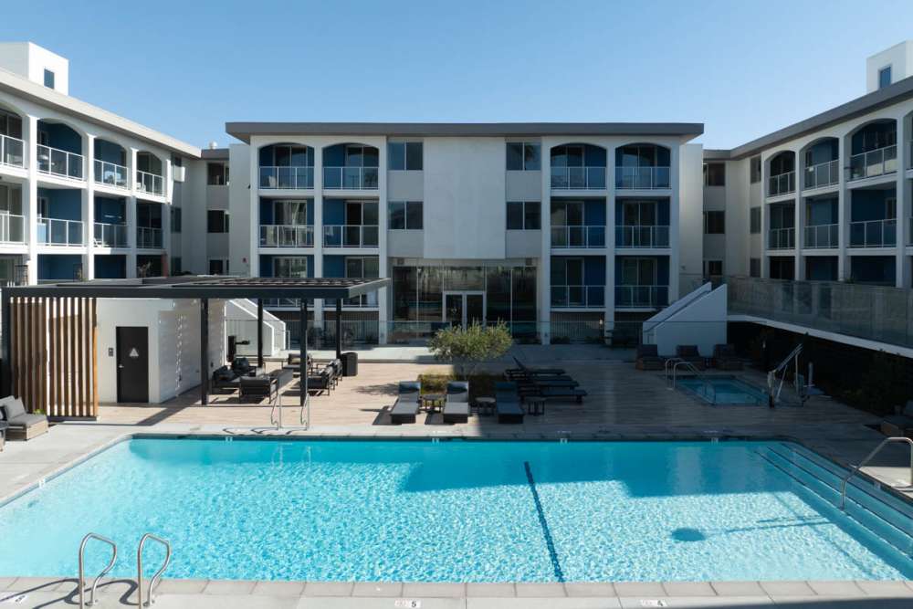 Luxury swimming pool with lounge chairs and cabana at Dolphin Marina Apartments in Marina Del Rey, California