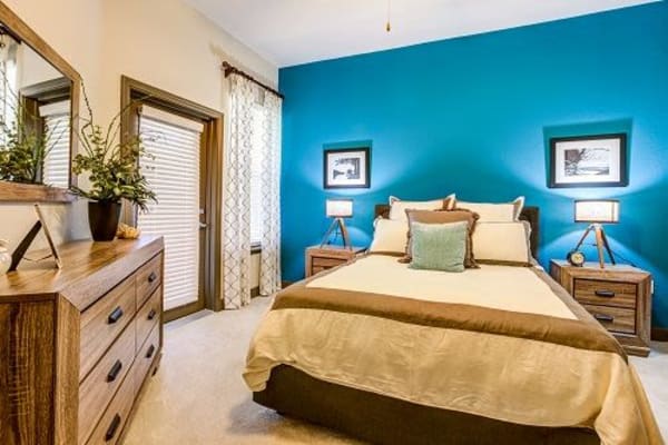 Carpeted bedroom with full-size bed and matching wooden end tables at Addison at Tampa Oaks in Temple Terrace, Florida