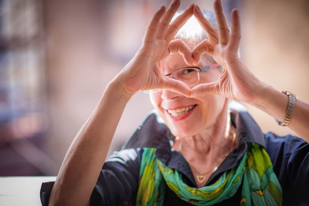 Caretaker making a heart symbol with her hands at Oxford Vista Wichita in Wichita, Kansas