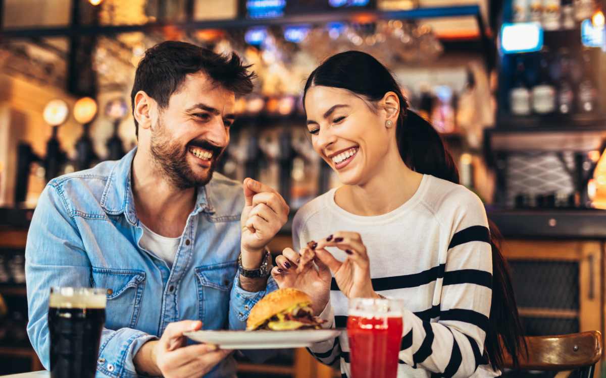 A couple sharing a meal and drinks in a restaurant near Ascent Apartment Homes in Asheville, North Carolina