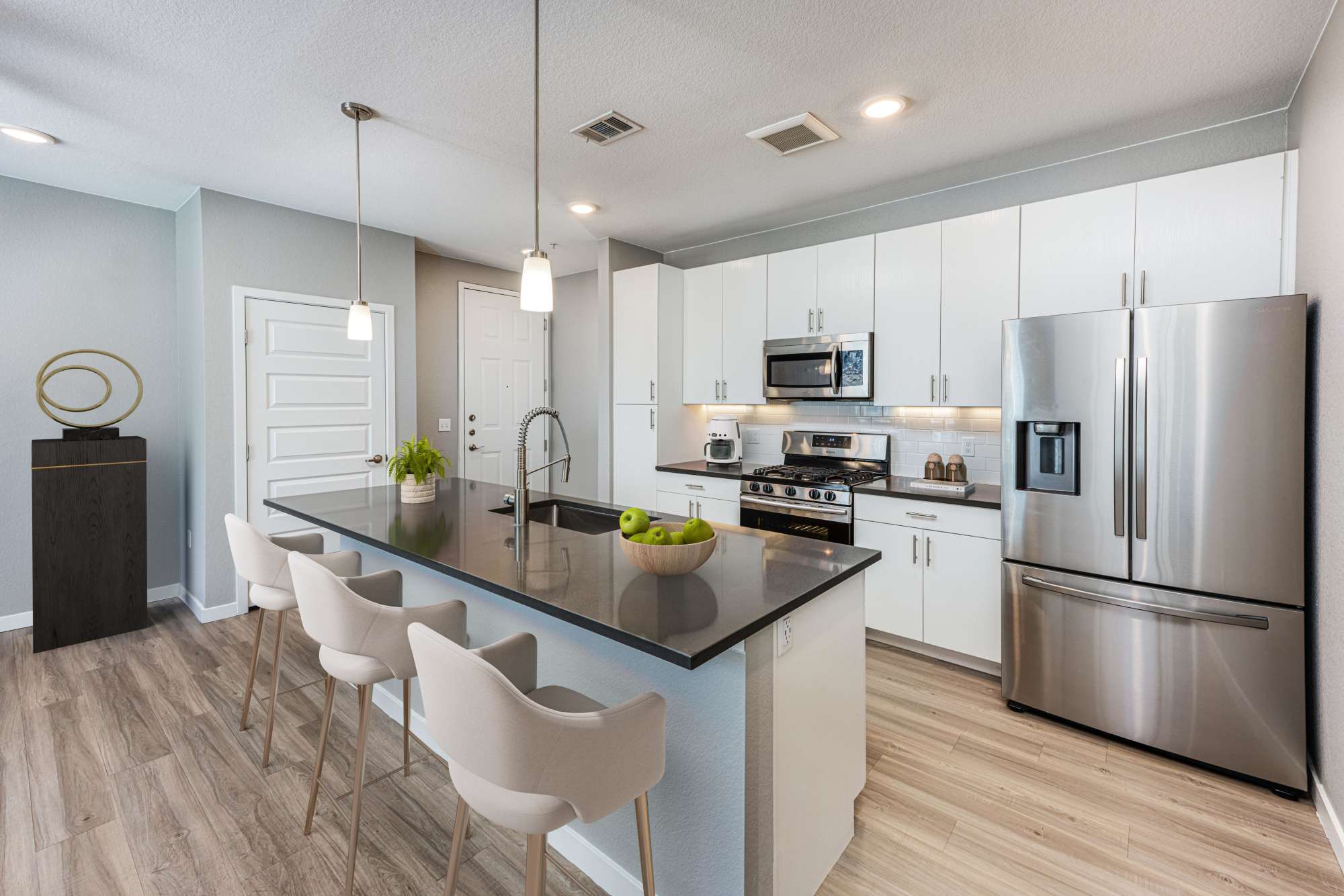 Model apartment kitchen with barstool at Hawthorne Hill Apartments in Thornton, Colorado