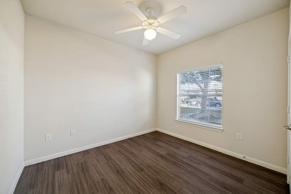 Charming bedroom with warm wood flooring and abundant natural light at Arbor Pines in Orange, Texas.