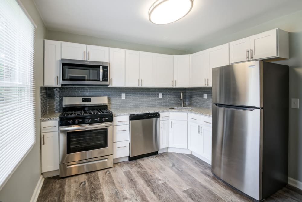 Kitchen with stainless steel appliances, granite countertops, and modern white cabinets