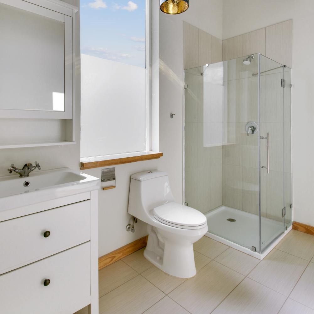 Bright bathroom with commode, shower and large window at The Lofts at 305 in Bryan, Texas