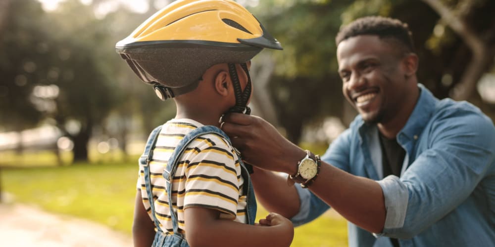 Father putting a bike helmet on his son at a park near Amber Grove Apartments in Marietta, Georgia