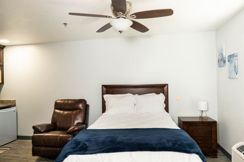 resident bedroom with ceiling fan, bed, comfy chair and side table at The Club at Haines City in Haines City, Florida