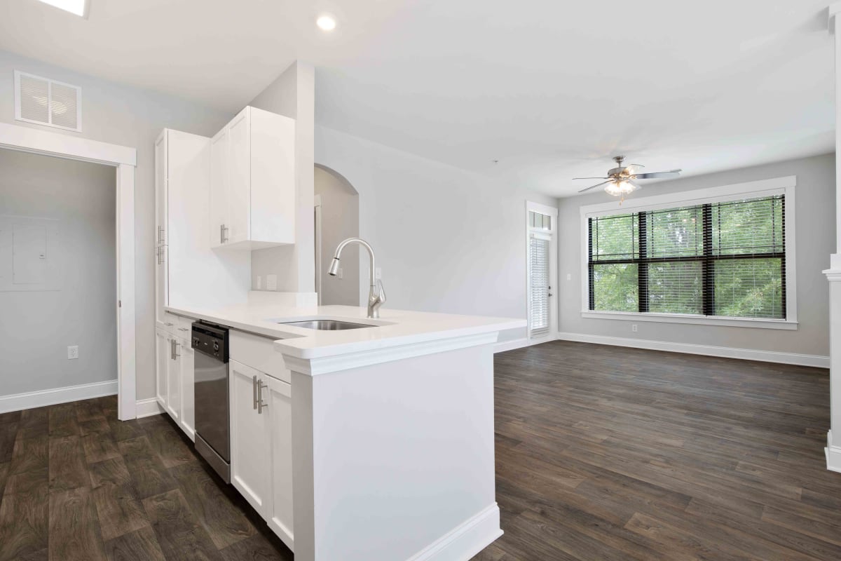 Apartment living room and kitchen with wood-style flooring at The Apartments At Blakeney in Charlotte, North Carolina