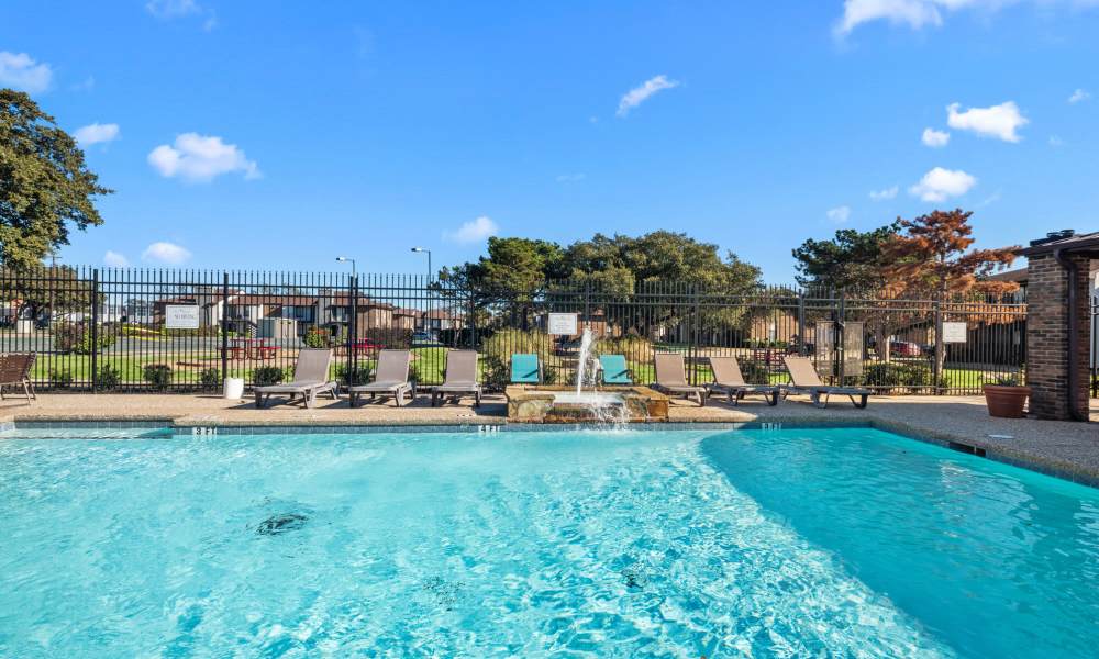 Swimming pool with lounge chairs at Pine Oaks Apartments in Mesquite, Texas
