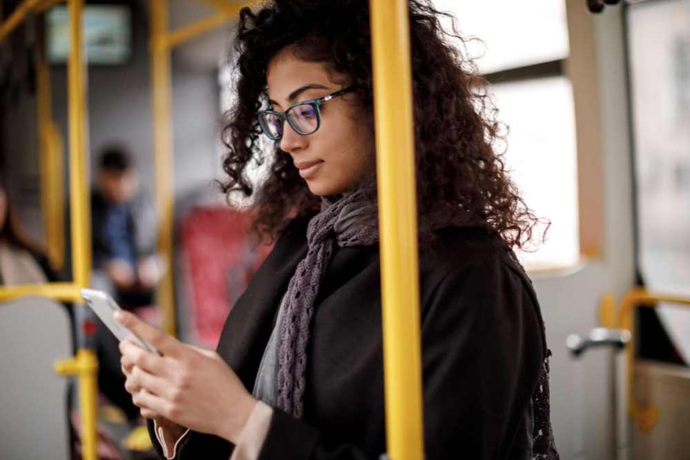 Woman on bus heading to shop and looking at phone while listening to music on headphones Maystone at Wakefield in Raleigh, North Carolina