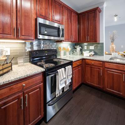 Kitchen with wooden-cabinetry and stove setup at Oaks at Sugarloaf in Lawrenceville, Georgia