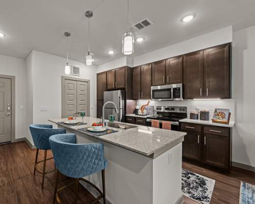Modern kitchen with stainless-steel appliances and island countertop at Opal Point At Kyle in Kyle, Texas