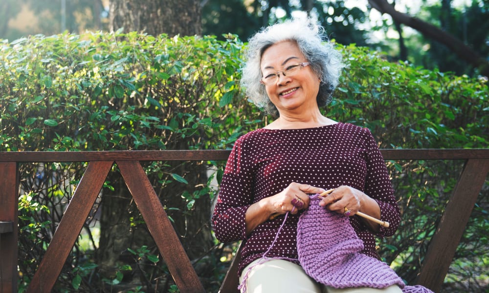 Senior woman knitting on a bench at Randall Residence of Auburn Hills in Auburn Hills, Michigan