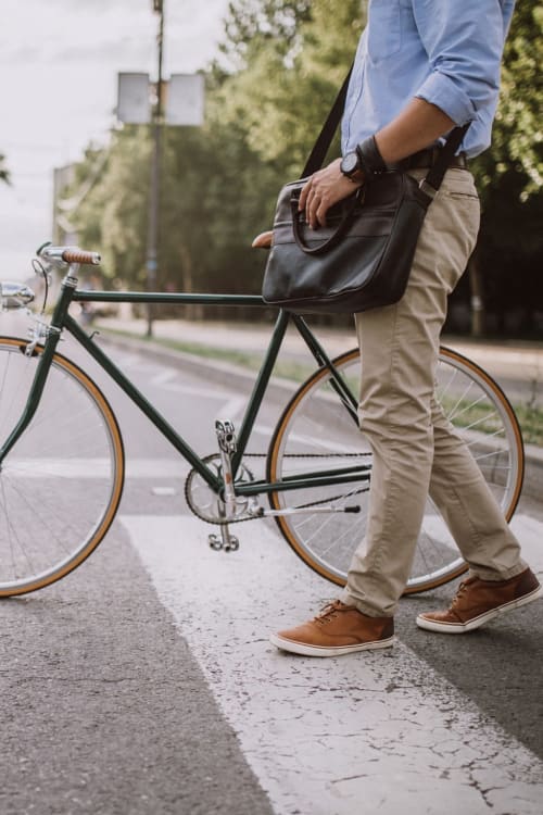 Man walking his bike across the street to be safe near The Bentley Apartments in Washington, District of Columbia
