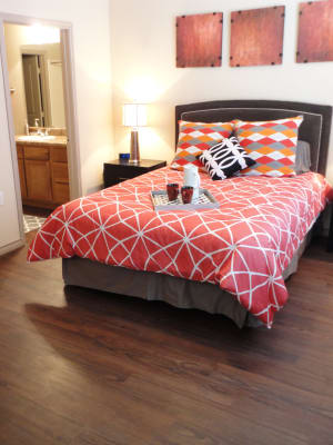 Elegant model master bedroom with hardwood style flooring at Anatole at City View in Lubbock, Texas