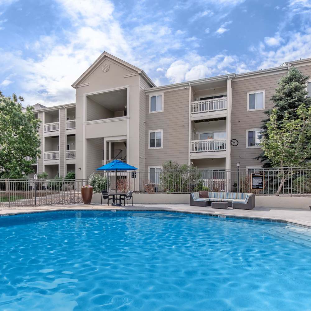Apartment building with shared swimming pool amenities at One Belmar Place in Lakewood, Colorado
