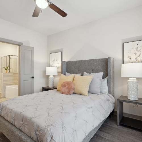 Model bedroom with ensuite bathroom and ceiling fan at Radius Wolf Ranch in Georgetown, Texas