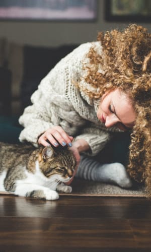 Resident giving her cat a scratch in the living room of their home at Summit Point Apartments in Mesquite, Texas