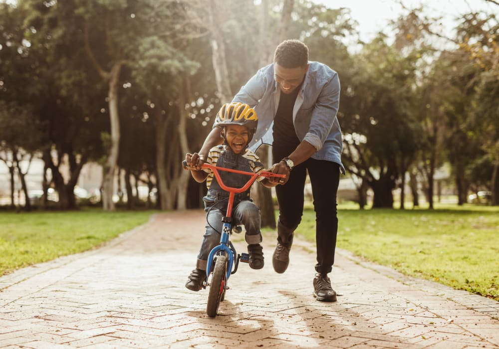 Father teaching his son how to ride a bike at The Abbey at Energy Corridor in Houston, Texas