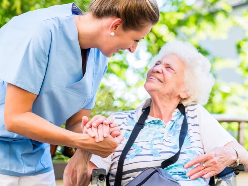 Caretaker wrapping their arm around the adjacent seated resident at The Residences on Forest Lane in Montello, Wisconsin