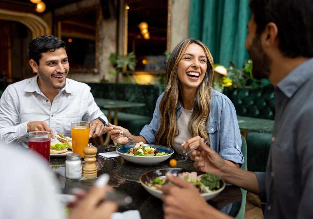Friends enjoying a lively meal at a cozy restaurant at Messina Luxury Apartments in New Smyrna Beach, Florida