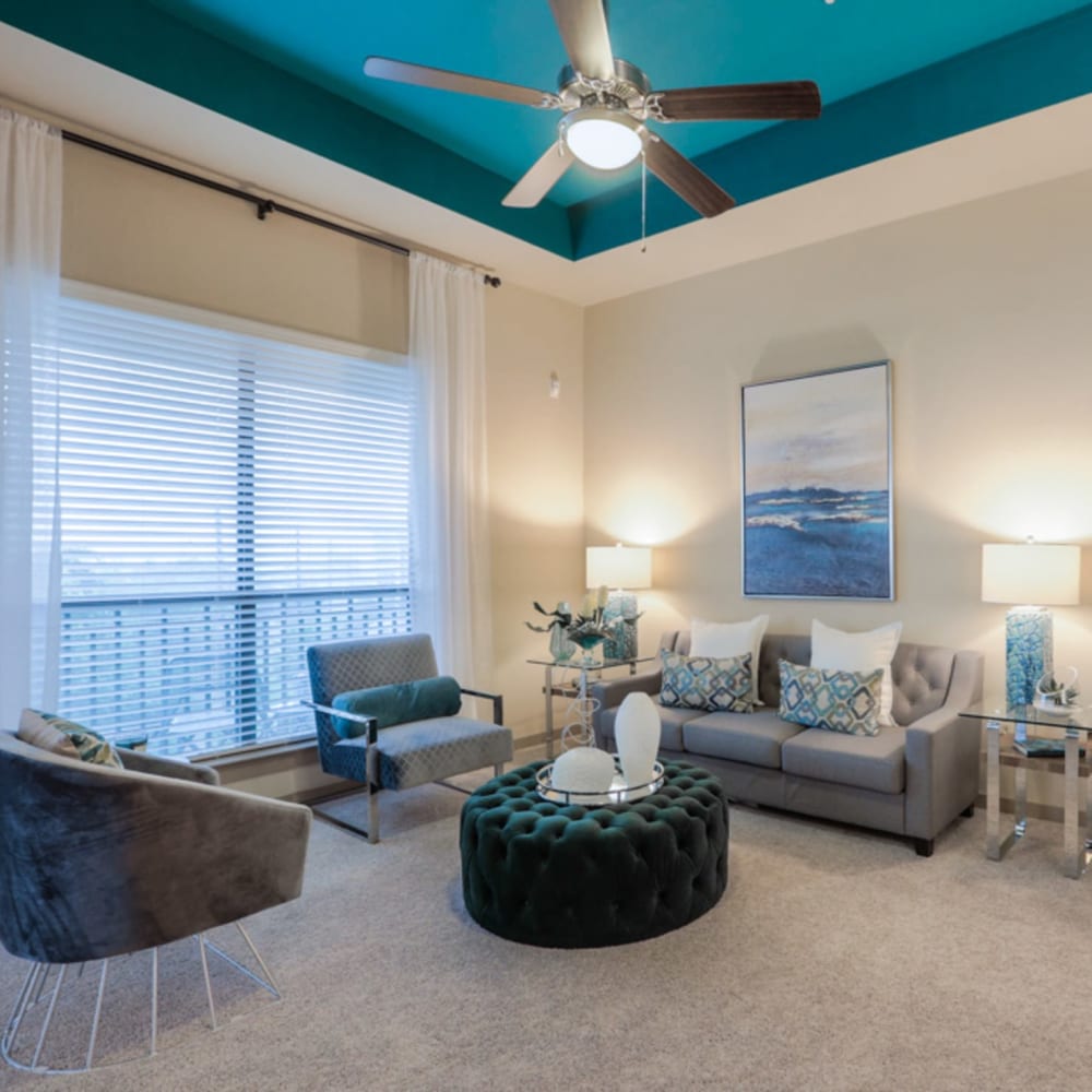 Spacious living room with plush carpeting and a ceiling fan at Imperial Lofts in Sugar Land, Texas