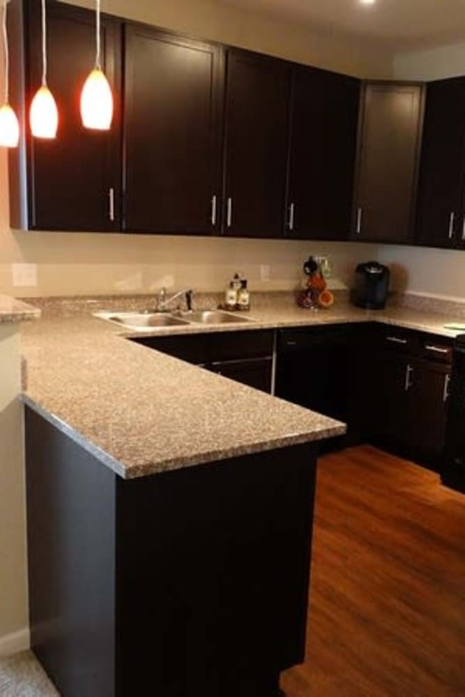 Kitchen with granite counters and wood style flooring at Oak Grove Crossing Apartments in Newburgh, Indiana