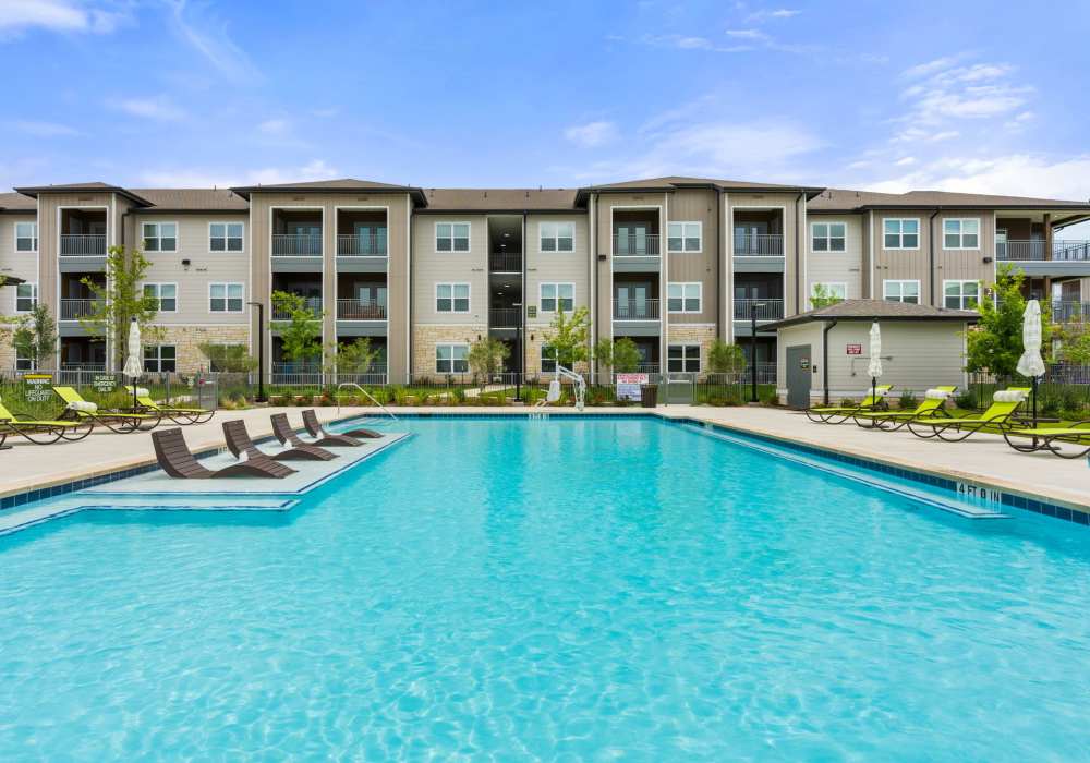 Resort-style pool with loungers at Walnut Springs in Seguin, Texas