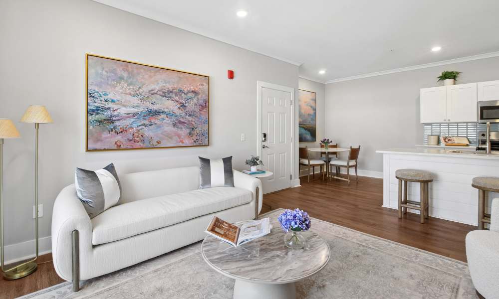 Bright living area with wood-style flooring, modern kitchen, and cozy dining space at Everett at Port Wentworth in Port Wentworth, Georgia