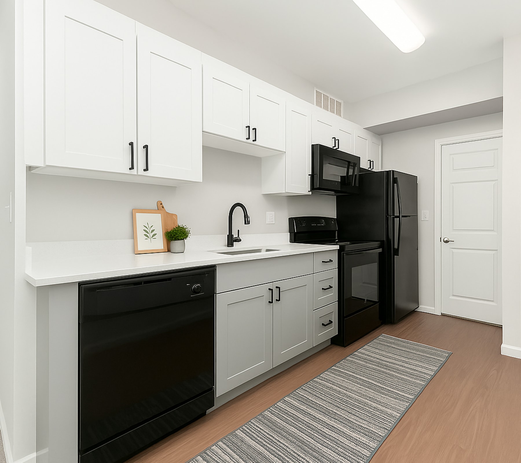 Newly renovated, modern kitchen with white cabinets and black appliances at Mazza Grandmarc in College Park, Maryland