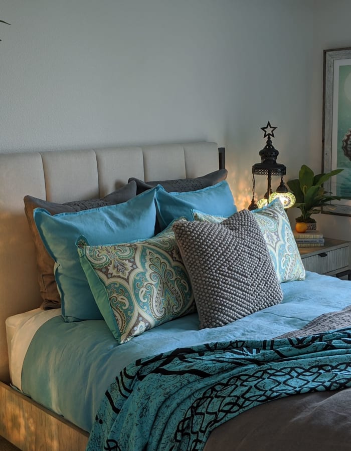 Furnished bedroom with multiple decorative pillows on bed at Vespaio in San Jose, California