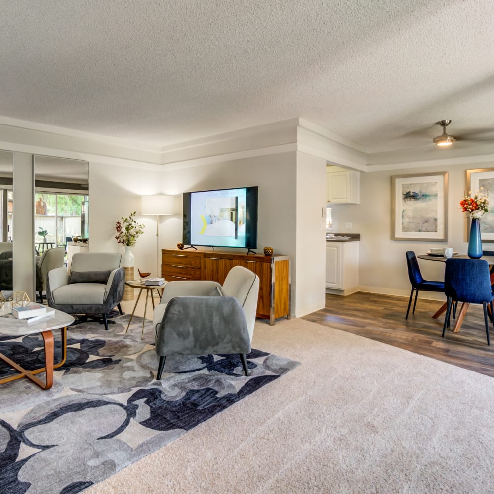 Open-concept living and dining areas with a ceiling fan and plush carpeting in a model home at Sofi Fremont in Fremont, California