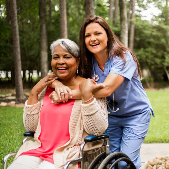 A resident and a CNA outside at an Americare community