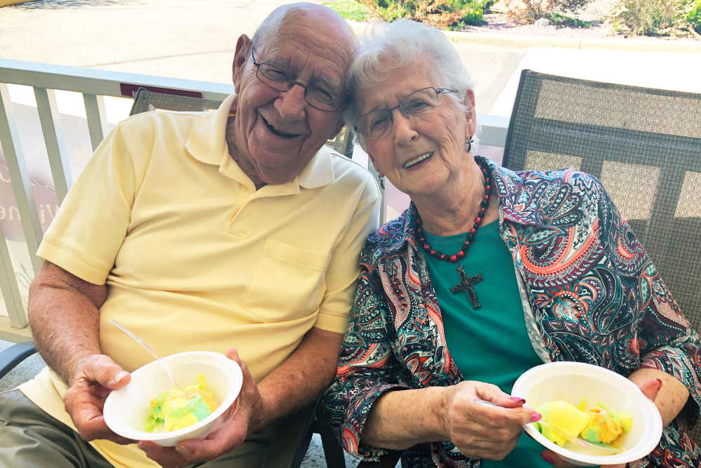 Cheerful resident couple with a dessert at HeatherWood Assisted Living & Memory Care in Eau Claire, Wisconsin