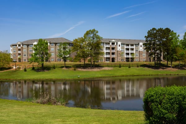 Exterior view of Haywood Reserve Apartment Homes with a large pond and expansive greenspace in Greenville, South Carolina