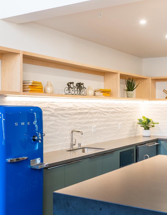 Bright kitchen featuring blue smeg refrigerator, island, modern cabinetry, and decorative plants on shelves at Exhibit at J Town in San Jose, California