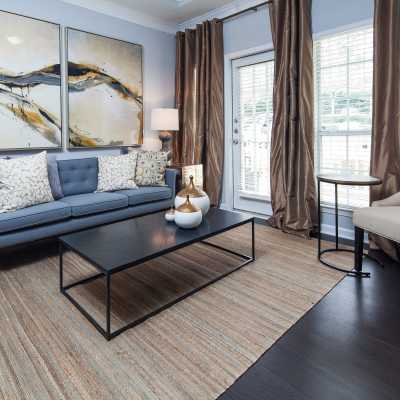 Living room with large windows and carpet flooring at Oaks at Sugarloaf in Lawrenceville, Georgia