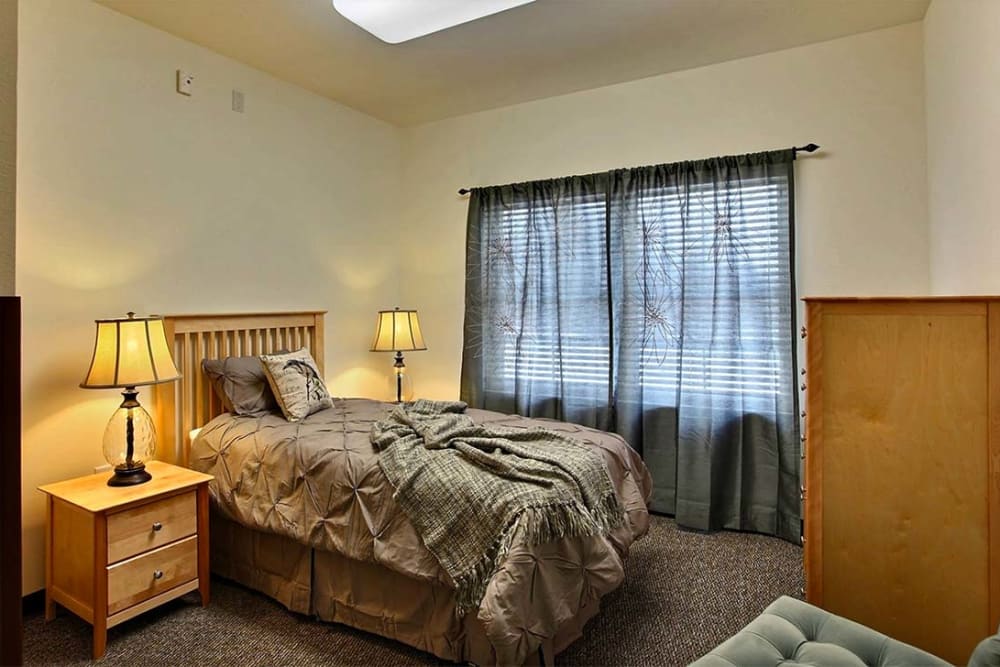 Cozy resident bedroom with side table and dresser at Milestone Senior Living Woodruff in Woodruff, Wisconsin.