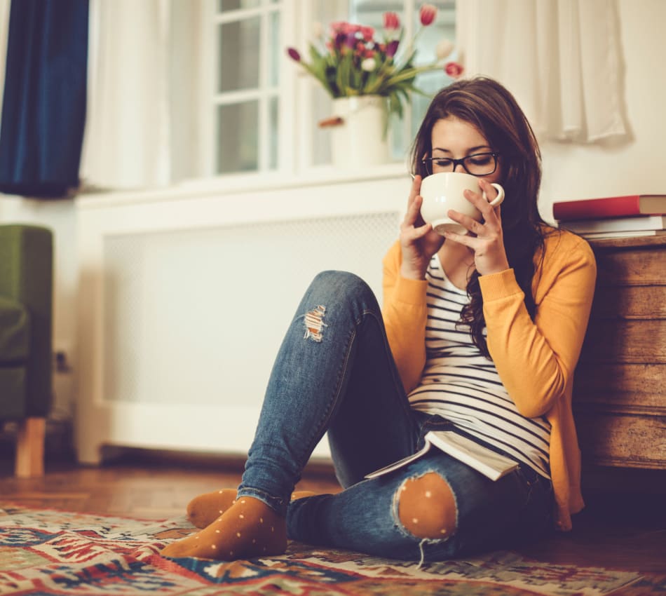 Resident relaxing with a cup of tea on the floor of the living area of her new home at Terra Martinez in Martinez, California