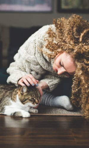 Resident giving her cat a scratch in the living room of their home at Rivercrest in Waco, Texas