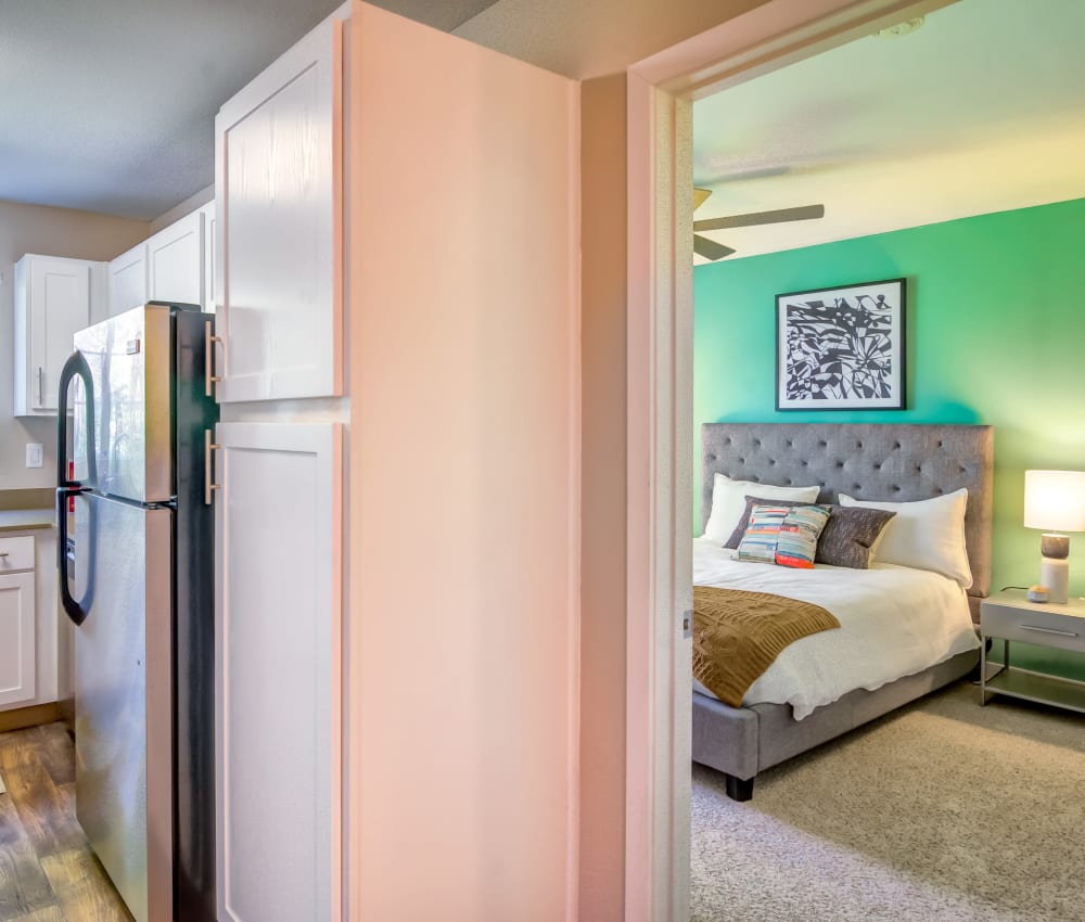 Bedroom with a ceiling fan next to the modern kitchen of a model home at Sofi at Murrayhill in Beaverton, Oregon