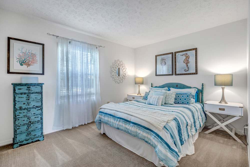 Spacious bedroom with large bed, side table lamp, cupboard and large window at Lake Carlton Arms in Lutz, Florida